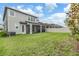 Lush, green backyard of a modern home with a screened lanai and white fence at 7276 Notched Pine Bnd, Wesley Chapel, FL 33545