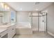 Bright bathroom featuring double vanity sinks, soaking tub, and glass-enclosed shower at 7276 Notched Pine Bnd, Wesley Chapel, FL 33545