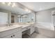 Bathroom featuring dual sinks, soaking tub, and a separate glass-enclosed shower at 7276 Notched Pine Bnd, Wesley Chapel, FL 33545