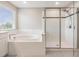 Modern bathroom featuring a soaking tub and a glass-enclosed shower with stylish tiling at 7276 Notched Pine Bnd, Wesley Chapel, FL 33545