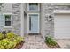 Charming home exterior featuring stone accents, a light blue front door, and manicured landscaping at 7276 Notched Pine Bnd, Wesley Chapel, FL 33545