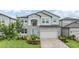 Two-story home with stone accents, a manicured lawn, paver driveway, and light blue shutters at 7276 Notched Pine Bnd, Wesley Chapel, FL 33545