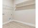Laundry room features wood-look tile flooring and multiple white wire and wood shelving units at 7276 Notched Pine Bnd, Wesley Chapel, FL 33545