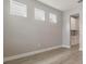 Bright, empty room with light gray walls, wood-look tile floors, and 3 windows facing front at 7276 Notched Pine Bnd, Wesley Chapel, FL 33545