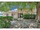 Home exterior featuring brick accents, well-maintained hedges, mature trees, and partially shaded lawn at 7309 Monterey Blvd, Tampa, FL 33625