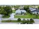 Aerial view of single-story blue home on a manicured lawn with palm trees and a long driveway at 8679 Burning Tree Cir, Seminole, FL 33777