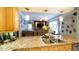 Bright kitchen with a stone island, stainless sink, and view into the comfortable living room at 8679 Burning Tree Cir, Seminole, FL 33777