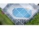 Aerial view of a screened-in pool with surrounding lounge chairs and green grass at 8679 Burning Tree Cir, Seminole, FL 33777