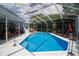 Inviting screened-in pool with lounge chairs, umbrella, and a view of the lush backyard at 8679 Burning Tree Cir, Seminole, FL 33777