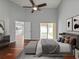 A bright primary bedroom boasts wood floors, a sliding door, and an upholstered bed with a bench at 9008 Egret Cove Cir, Riverview, FL 33578