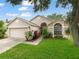 Charming single-story home with a well-manicured lawn, mature trees, and an attached two-car garage at 9008 Egret Cove Cir, Riverview, FL 33578