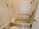 Bathroom featuring white tile, a bathtub with safety bar and a toilet at 907 San Carlos Ne Ave, St Petersburg, FL 33702