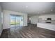 Open-concept living room with light gray walls, wood flooring and sliding glass doors at 9921 Surrey Rose Dr, San Antonio, FL 33576
