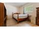 Bright bedroom features a wooden bed frame, window, tile flooring, and plenty of natural light at 9927 Woodridge Ct, Port Richey, FL 34668