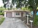 Charming single-story home with a driveway, attached garage, and a mature shade tree in the front yard at 9927 Woodridge Ct, Port Richey, FL 34668
