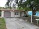 Charming single-story home with a driveway, attached garage, and a mature shade tree in the front yard at 9927 Woodridge Ct, Port Richey, FL 34668