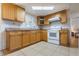 Well-lit kitchen features tile floors, light wood cabinets, and modern white appliances at 9927 Woodridge Ct, Port Richey, FL 34668