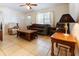 Comfortable living room features tile floors, a ceiling fan, and a large window that provides natural light at 9927 Woodridge Ct, Port Richey, FL 34668