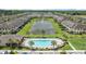 Community aerial view highlighting the pool, central pond, and neatly arranged townhomes surrounded by lush greenery at 11526 Crowned Sparrow Ln, Tampa, FL 33626