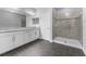 Modern bathroom with dual sinks, white cabinets, and a walk-in shower with tiled walls at 11526 Crowned Sparrow Ln, Tampa, FL 33626