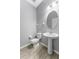 Powder room with hardwood floors, light gray walls, and a modern pedestal sink at 11526 Crowned Sparrow Ln, Tampa, FL 33626