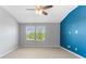Spacious bedroom featuring carpet flooring, a ceiling fan, and two windows with views of the outside at 11526 Crowned Sparrow Ln, Tampa, FL 33626