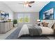 Serene bedroom featuring a soothing blue accent wall, plush bedding, and ample natural light from large windows at 11526 Crowned Sparrow Ln, Tampa, FL 33626