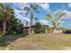 Charming single-story home featuring mature palm trees and lush landscaping in a serene yard at 1162 Music Ln, North Port, FL 34286