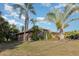 Attractive single-story home showcasing mature palm trees with tropical landscaping and a well-maintained lawn at 1162 Music Ln, North Port, FL 34286