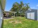 Expansive backyard with covered patio, lush lawn, shed, and mature trees at 12920 124Th Ave, Largo, FL 33774