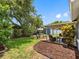 A beautifully landscaped backyard with a covered patio, outdoor seating, and mature trees at 12920 124Th Ave, Largo, FL 33774