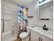 Clean bathroom featuring a shower-tub combo, modern vanity with marbled countertop, and decorative shower curtain at 13928 Raie Ave, Hudson, FL 34667