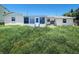 Exterior view of home showing enclosed porch and AC unit with overgrown lawn at 13928 Raie Ave, Hudson, FL 34667