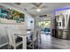 Charming dining room with gray plank floors, view to outdoor patio, stainless refrigerator and beachy decor at 13978 Barbados Dr, Seminole, FL 33776