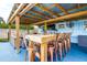Stylish covered patio featuring an outdoor dining table with seating for ten, ceiling fans, and a built-in bar area at 13978 Barbados Dr, Seminole, FL 33776