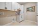 Bright laundry room features white cabinetry, a stainless steel faucet, and neutral paint at 14063 Wineberry Dr, Dade City, FL 33525