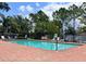 Community swimming pool with lounge chairs, surrounded by mature trees and a secure fence at 1427 Hillview Ln, Tarpon Springs, FL 34689