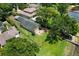 Spacious fenced backyard featuring green grass, mature trees, and a home with a lovely deck and lake access at 14808 Lake Magdalene Cir, Tampa, FL 33613
