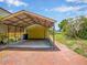 Open carport featuring a brick driveway and a garage behind it, providing ample parking space and storage at 14808 Lake Magdalene Cir, Tampa, FL 33613