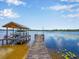 Picturesque lakeside property featuring a private dock with a covered boat lift and scenic water views at 14808 Lake Magdalene Cir, Tampa, FL 33613