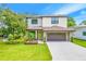 Two-story home with a well-manicured lawn, garden bed, two-car garage, and neutral exterior paint at 14808 Lake Magdalene Cir, Tampa, FL 33613