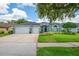 Charming one-story home featuring a well-manicured lawn, garden beds, and a three-car garage at 15309 Palomapark Ln, Lithia, FL 33547