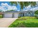 Stylish light gray home with a two car garage, elegant windows, and lush landscaping at 15309 Palomapark Ln, Lithia, FL 33547