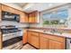 Updated kitchen with stainless-steel gas range, microwave, granite counters, and bright window at 15609 Gardenside Ln, Tampa, FL 33624