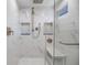 Modern walk-in shower featuring textured white tile, built-in shelving, and a shower bench at 15609 Gardenside Ln, Tampa, FL 33624