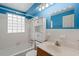 Bright bathroom features a tiled shower/tub, vanity with storage, and blue accents at 1579 Palmetto St, Clearwater, FL 33755