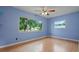 Sunlit bedroom with hardwood floors, two windows, and views of the lush greenery outside at 1579 Palmetto St, Clearwater, FL 33755