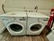 Close-up of the front-load white washer and dryer with laminate floors at 1813 E Wood St, Tampa, FL 33604