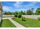 A backyard with a concrete path, green grass and landscaping, and a white privacy fence at 19974 Bluebird Meadow Dr, Lutz, FL 33558