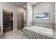 Bathroom features a bathtub, tiled shower, and access to a walk-in closet at 19974 Bluebird Meadow Dr, Lutz, FL 33558